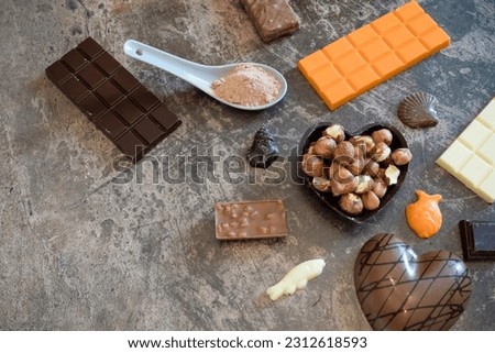 Background with chocolates of different shapes and flavors, hazelnuts and cocoa powder