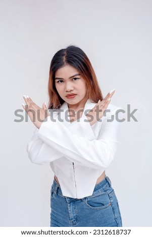 A serious and unimpressed young woman doing an x-sign with her arms. Isolated on a white background.