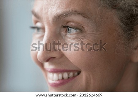 Happy pretty face of mature senior lady with natural makeup close up. Positive retired woman looking away with toothy smile . Beauty, dental care, elderly healthcare model facial close up