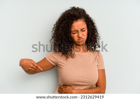 Young Brazilian woman isolated on blue background having a liver pain, stomach ache.