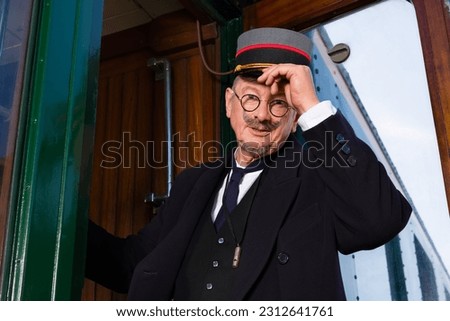 Reenactment scene with authentic 1927 1st class train carriage and a retro train conductor at departure Royalty-Free Stock Photo #2312641761