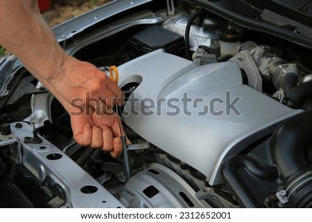 mechanic checking oil level in car engine Royalty-Free Stock Photo #2312652001