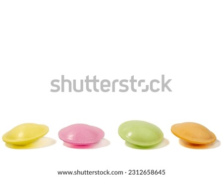 Sweet candies in the shape of a UFO in different colors on a white background. Flying saucers sugar paper in the shape of a spaceship with sherbet. Royalty-Free Stock Photo #2312658645