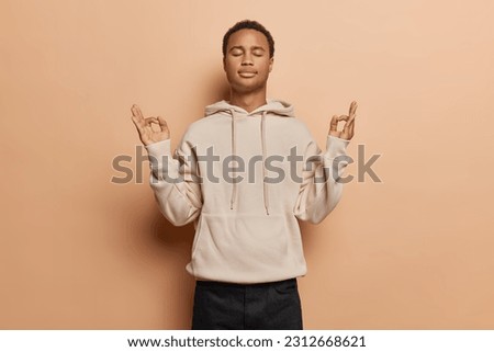 Tranquil young man exudes sense of calmness as peacefully closes his eyes practices mindful breathing and yoga captures essence of inner peace and relaxation dressed casually isolated over brown wall Royalty-Free Stock Photo #2312668621