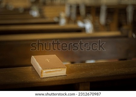 Bible on the church bench. God's word in one little book. Soft selective focus. Artificially created grain for the picture