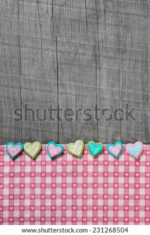 Shabby chic grey wooden background with hearts on a pink white checkered frame.