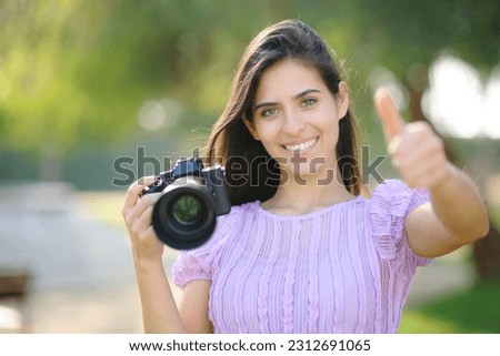 Front view portrait of a happy photographer gesturing thumbs up