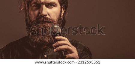 Male attends karaoke. Bearded man singing with microphone. Male singing with a microphones. Man beard holding a microphone.