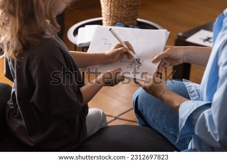 A girl at a psychologist's appointment draws a test drawing, low self-esteem and psychological problems in a child, a photo from the back. High quality photo