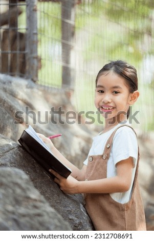 The girl is having a fun field trip to the zoo and took notes. Royalty-Free Stock Photo #2312708691