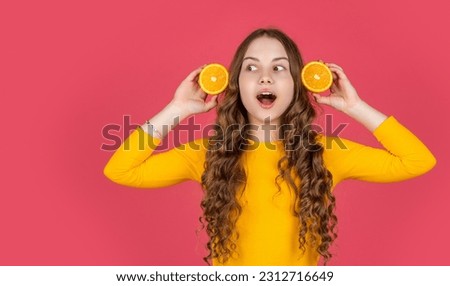 surprised teen kid hold orange fruit on pink background