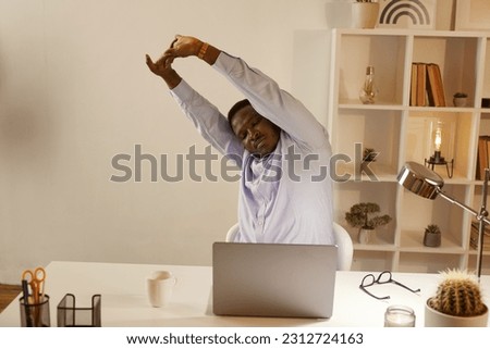 Employee Stretching At Office Desk At Work, tired African American office worker