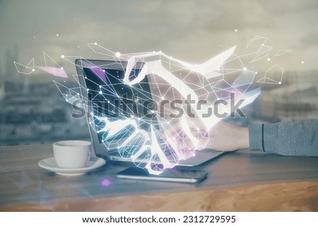 Handshake hologram drawing with businessman working on computer on background. Double exposure.