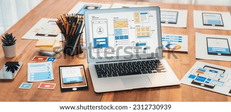 Digital and paper wireframe designs for web or mobile app UI UX display on laptop computer screen. Panoramic shot of developer workspace for brainstorming and design application framework. Scrutinize Royalty-Free Stock Photo #2312730939