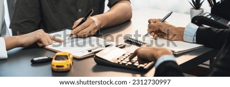 Car dealer calculate interest rate and costs of car loan, offering financial and insurance service while customer client reading on term and agreement on contract in dealership office. Prodigy Royalty-Free Stock Photo #2312730997