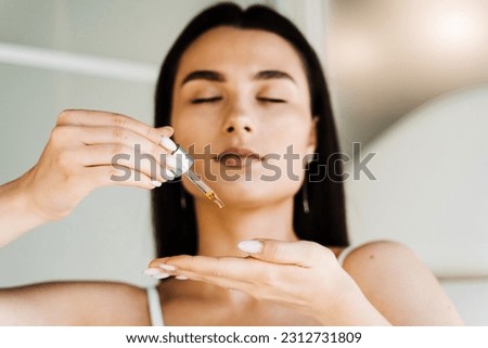 Girl with hyaluronic acid or serum pipette in hands close-up. Young woman is applying moisturizing serum on skin Royalty-Free Stock Photo #2312731809