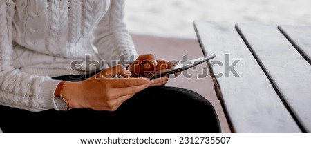 Shot of chinese woman at outdoor cafe by the pond using digital tablet. Young woman reading ebook on her digital tablet. Royalty-Free Stock Photo #2312735507