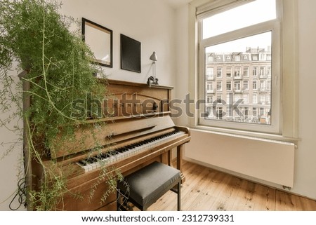 a living room with an old piano and some plants in the window simh is on the wall next to the piano Royalty-Free Stock Photo #2312739331