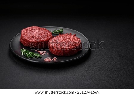 Fresh raw ground beef burger patty with salt and spices on textured concrete background
