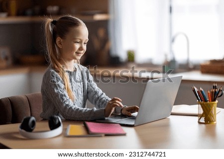 Coding For Kids. Cute Little Girl Using Laptop While Sitting At Desk At Home, Smiling Preteen Female Child Attending Programming Courses, Looking At Computer Screen And Typing On Keyboard Royalty-Free Stock Photo #2312744721