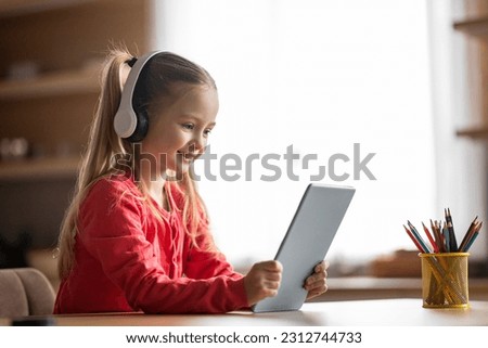 Great App. Portrait Of Cute Little Girl Using Digital Tablet At Home, Smiling Preteen Female Child Wearing Wireless Headphones Browsing Educational Application On Modern Gadget, Copy Space