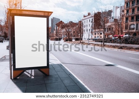 In Barcelona, a picturesque neighborhood is the backdrop for a beautiful sunny day. A white, empty mockup or billboard stands prominently at a bus station, creating a clean and clear aesthetic