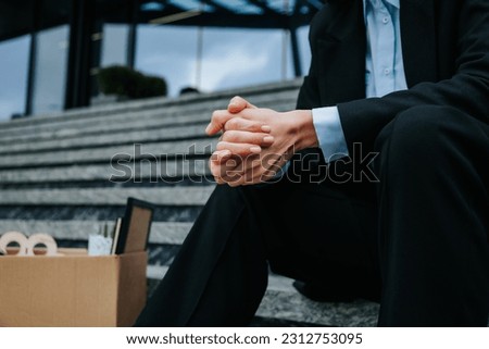 The struggle of losing work and being jobless is captured in this close-up of hands holding a carton box. From Work to Waste A Close-Up on Dismissal and Unemployment Royalty-Free Stock Photo #2312753095