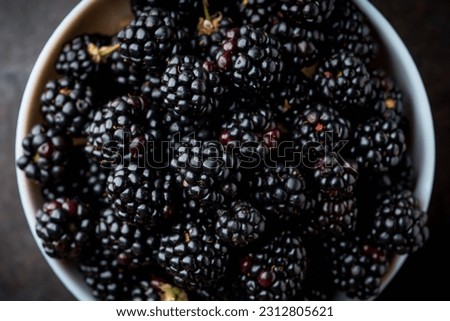 Blackberries in ceramic bowl on rustic wooden background. Selective focus. Shallow depth of field.