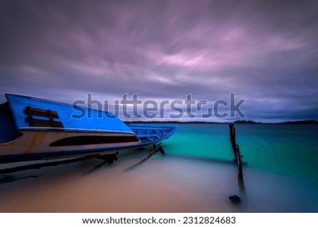 The beauty of the sunset in the Mentawai Islands, West Sumatra, Indonesia. Long exposure photo, the canoe parked in the yard on the white sandy beach.