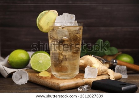 Glass of tasty ginger ale with ice cubes and ingredients on wooden table Royalty-Free Stock Photo #2312827339