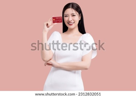 Portrait young Asian woman showing credit card isolated on pink background.