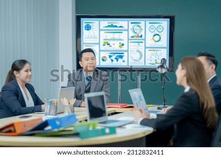 Office Conference Room Meeting Presentation: asian Businessman Talks, Uses Wall TV to Show Company Growth with Big Data Analysis, Graphs, Charts, Infographics. Multi-Ethnic e-Commerce Startup 