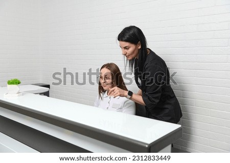 Medical staff talking behind a reception counter in modern outpatient hospital, medical clinic or beauty spa salon. Female doctor in stylish black uniform talking to administrator of dentistry clinic Royalty-Free Stock Photo #2312833449