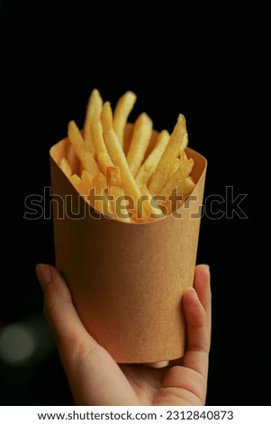 french fries in a paper cup on a black background