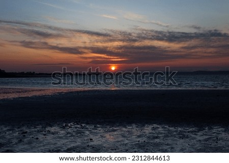 Sunset over Musselburgh beach, with views to the city of Edinburgh in Scotland on a sunny spring day. 	