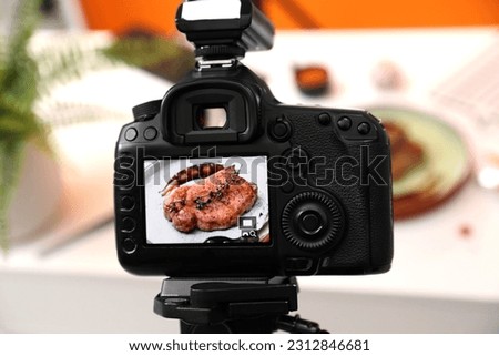 Professional camera with picture of meat medallion on display in photo studio, closeup. Food stylist
