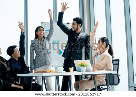 Asian business man and woman raise their hands up to express happiness and celebration for successful of the project in office.