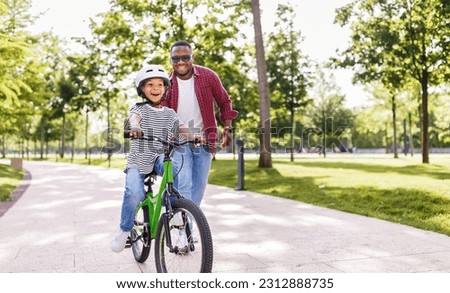 Happy african american family  father teaches boy son  to ride bike in  park   in nature
 Royalty-Free Stock Photo #2312888735