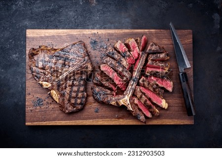 Modern style traditional barbecue dry aged wagyu porterhouse beef steak bistecca alla Fiorentina sliced and served as to view on a wooden design board  Royalty-Free Stock Photo #2312903503