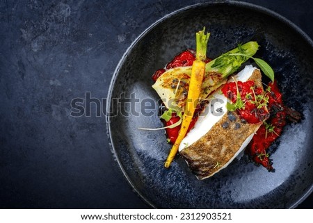 Modern style traditional fried skrei cod fish filet with fennel and tomato cream served as close-up in ceramic design bowl with copy space left