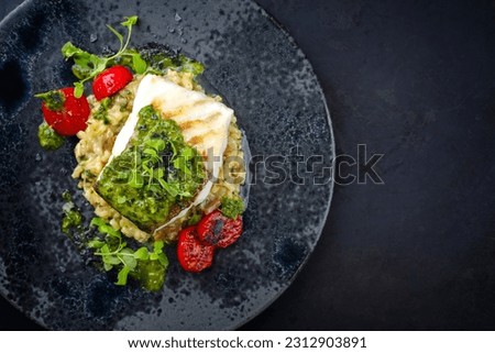 Modern style traditional fried skrei cod fish filet with mushroom rice risotto and oregano salsa relish served as top view on a Nordic design plate with copy space right