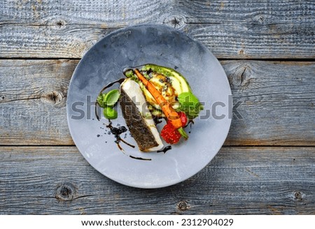 Modern style traditional fried skrei cod fish filet with mashed potato cream and coriander lime relish served as top view on a design plate with copy space 