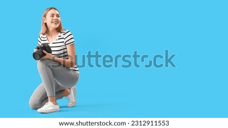 Female photographer with professional camera on light blue background with space for text