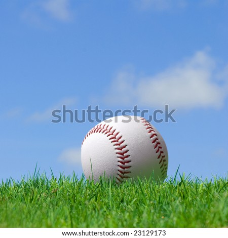 base ball in green grass field with blue sky background
