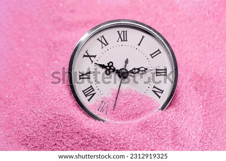 A clock on pink sand