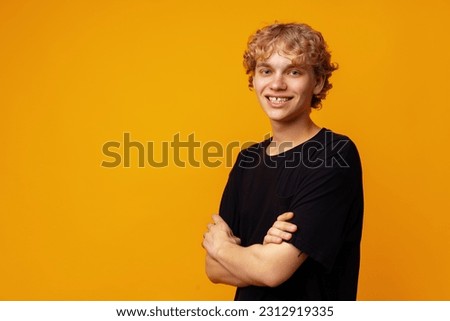 Young smiling happy caucasian man with blonde curly hair against yellow background