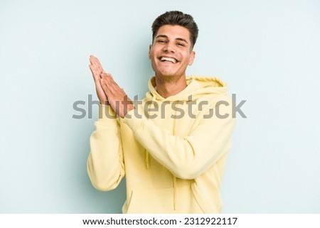 Young caucasian man isolated on blue background feeling energetic and comfortable, rubbing hands confident. Royalty-Free Stock Photo #2312922117