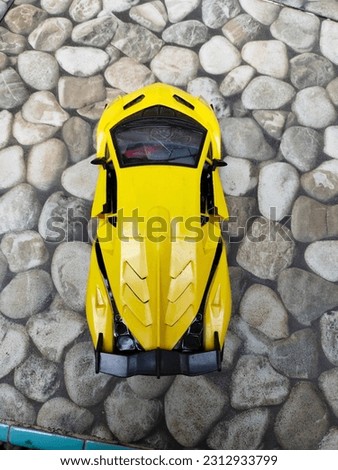 Yellow sports car toy with rock background