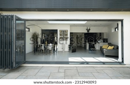 Stylish, open, bifold doors revealing interior of a designer, lifestyle, kitchen diner room. Royalty-Free Stock Photo #2312940093