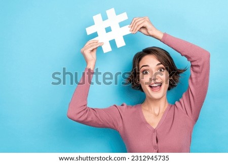Photo of pretty excited lady wear pink cardigan rising hash tag empty space isolated blue color background
